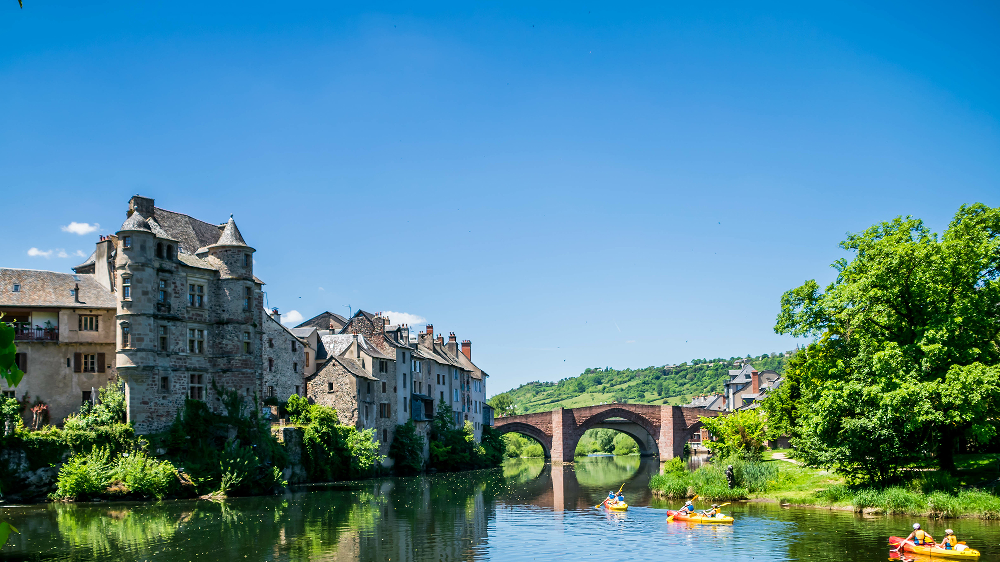 stunning French town along a riverbank with boats going along and under a bridge
